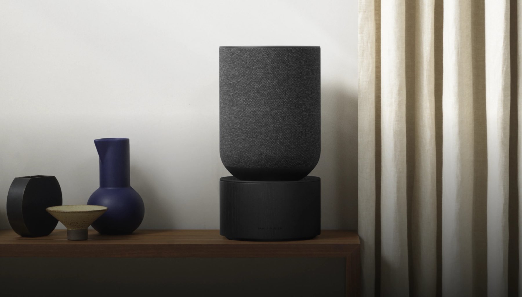 Beosound Balance pe o comodă, lângă ceramică.