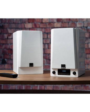 SVS Prime Wireless Pro, finisaj Piano Gloss White, perechea pe o comodă de lemn lângă un perete de cărămidă