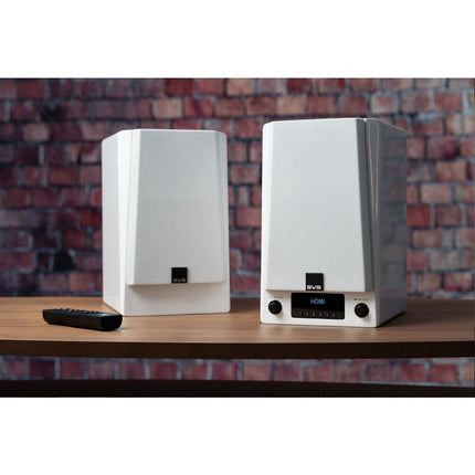 SVS Prime Wireless Pro, finisaj Piano Gloss White, perechea pe o comodă de lemn lângă un perete de cărămidă