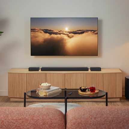 JBL Bar 1000MK2 върху шкаф със субуфера до него във всекидневна