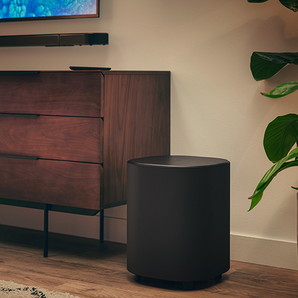 Безжичният субуфер на JBL Bar 1000MK2 на пода до шкафа за телевизора